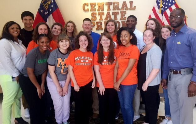 Students are pictured in front of a sign for Central State Prison