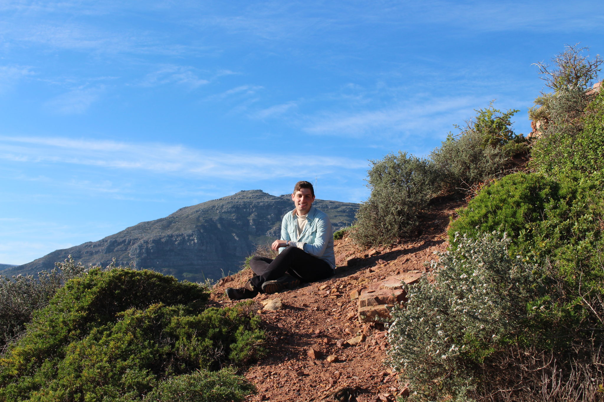 A Mercer student sits on a mountain in Africa.