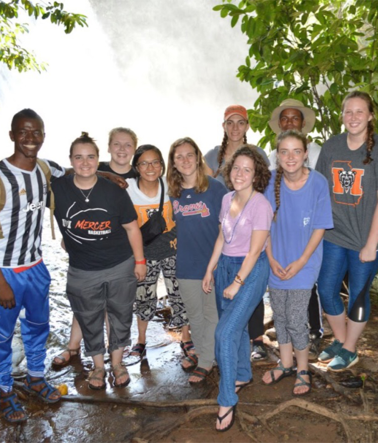 A group of students in front of a waterfall.