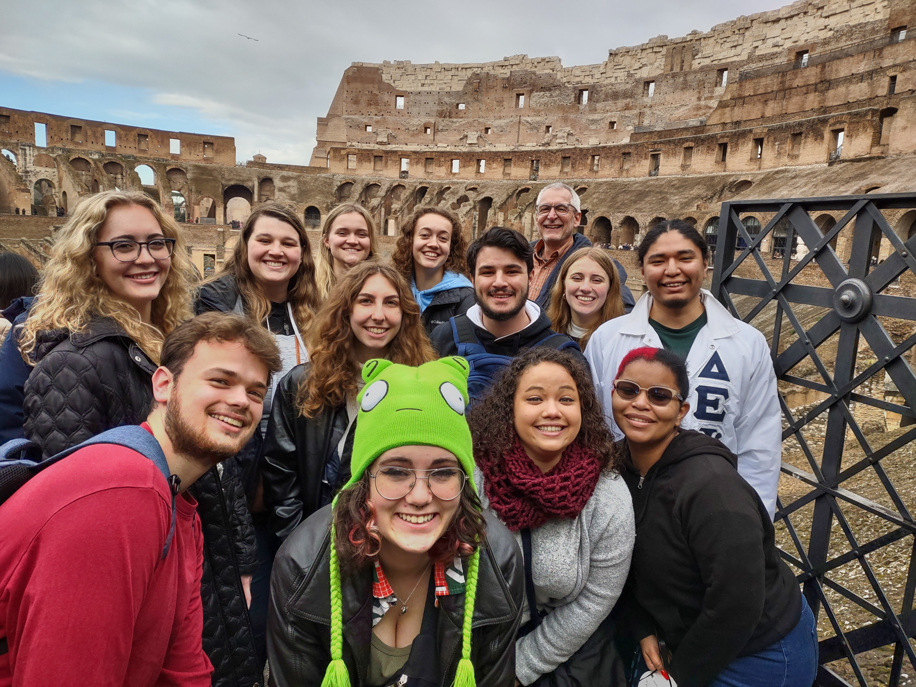 a group of students pose for a photo in front of the coloseeum