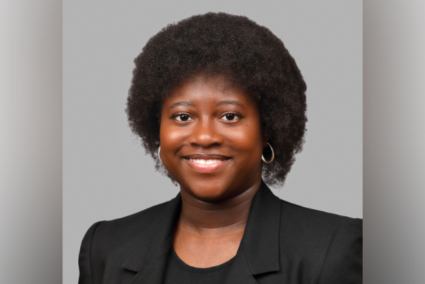 Headshot of Aaliyah Deen-Sesay wearing a black blazer against a gray background.