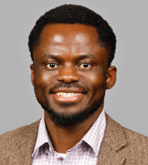 Headshot of Dr. Paul Atandoh, wearing a checkered collared shirt and a tweed jacket.