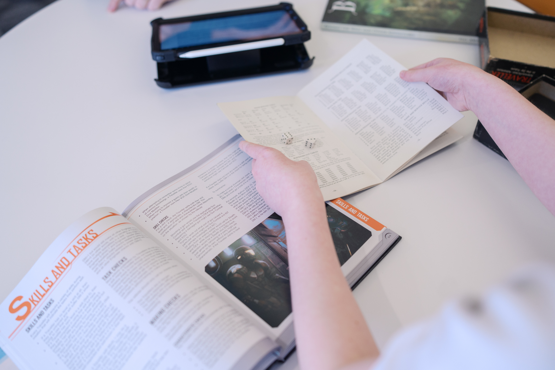 A person holds a notebook next to an open textbook that is on a page titled Skills and Tasks.