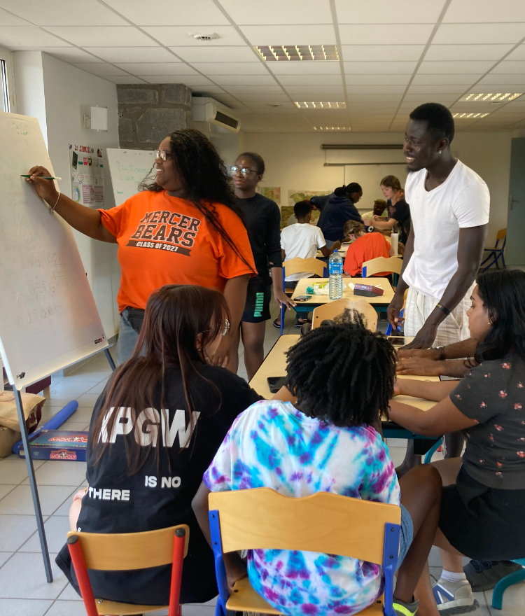 A Mercer student writes on a white board while others look on.