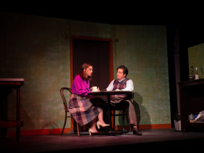 Two Mercer Theatre actors share an intimate conversation at a small cafe table during a scene in Grand Guignol.