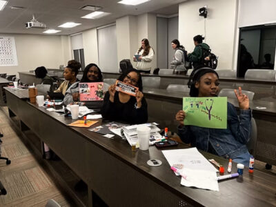 Mercer students hold up drawings they made at a Biology Mentorship Program event.
