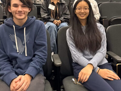 Four students sit in an auditorium.
