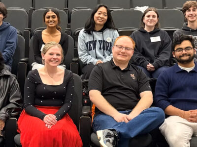 Ten students sit in an auditorium.